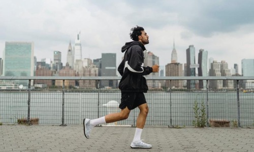 a person running on a stone path with a city skyline in the background