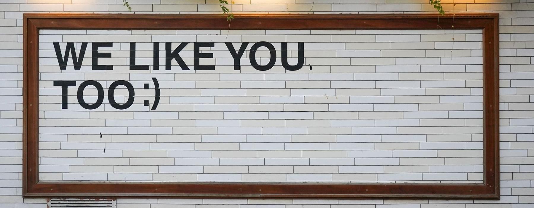 a sign on a tile wall that says, "We like you too"